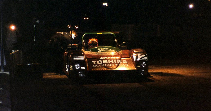 Alex Caffi patiently waiting while mechanics work feverishly to repair the right rear suspension of the #12 Doyle-Risi 333 SP s/n 018.  The car ended up spending over 30 minutes in the pits, loosing 18 laps and dropping from 3rd to 7th position.  By the end of the race, it had moved up to 6th place.
