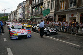 Pierre Delettre waves away the field from the main street in Spa in front of a large crowd