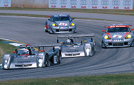 a formation of factory Cadillacs leads the Barbour Porsches